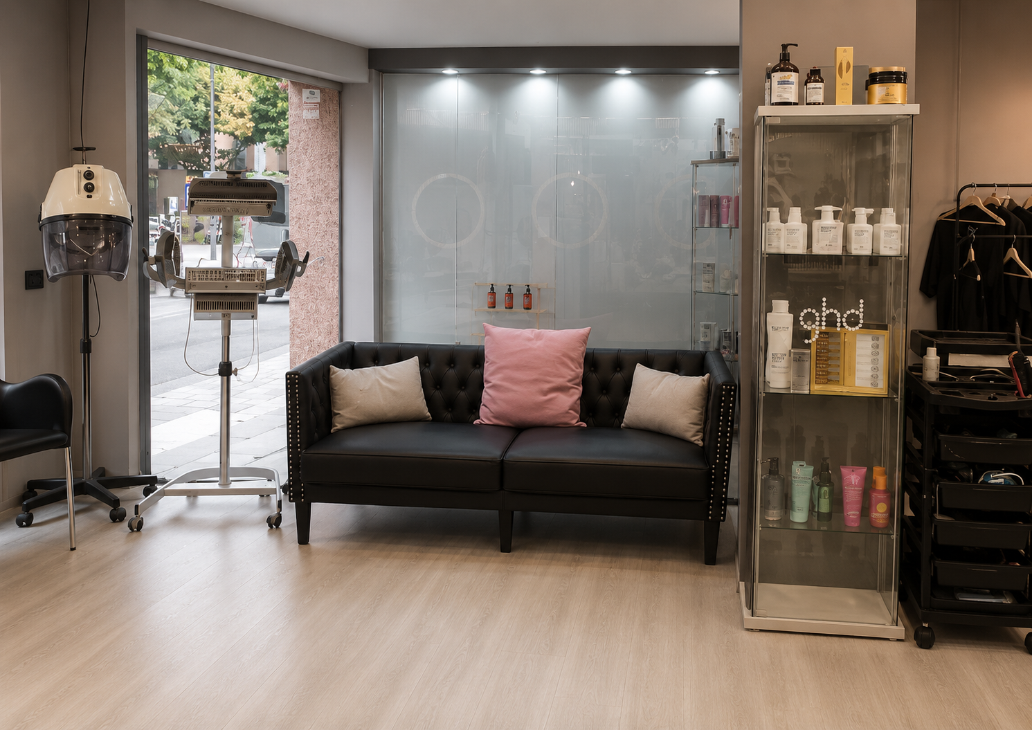 SOFA Zona de espera del salón Al Pelo Perruquers con sofá, secador de casco y estantería de productos capilares